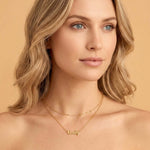 Woman wearing a Signature Name Necklace with the name Emily in gold against a plain background.