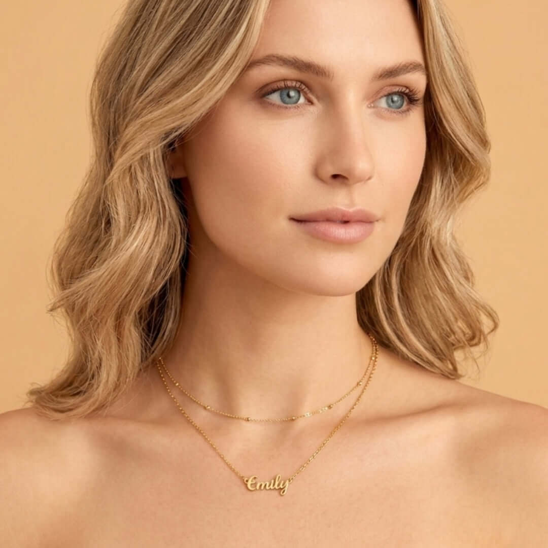 Woman wearing a Signature Name Necklace with the name Emily in gold against a plain background.