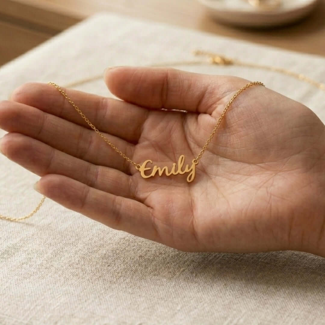 Signature Name Necklace in gold held in a hand, showcasing personalized jewelry design for custom names.