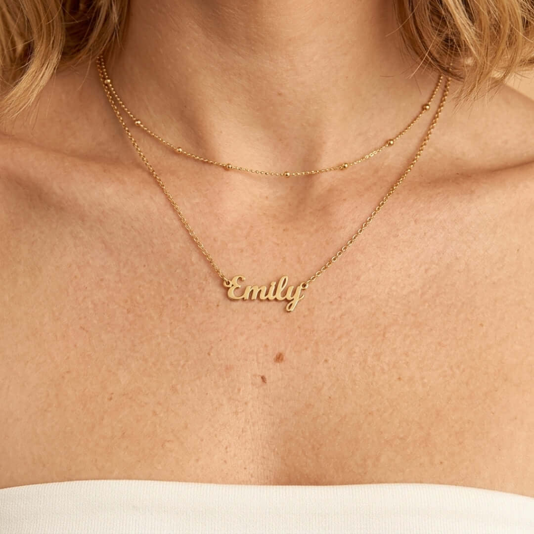 Signature Name Necklace worn in gold, featuring the name 'Emily' on two layered chains.