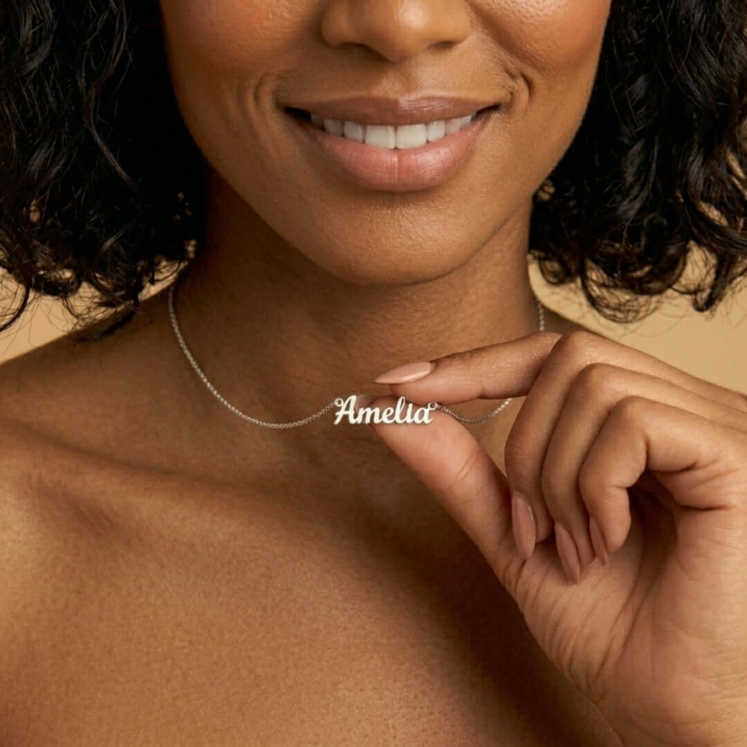 Close-up of a woman holding a Signature Name Necklace with the name 'Amelia' in silver, showcasing a personalized jewelry piece.