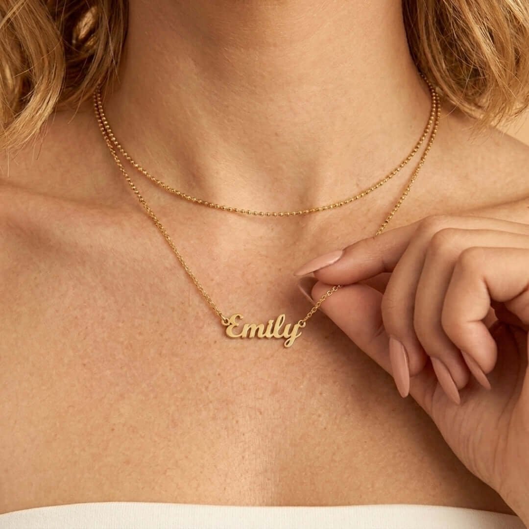 A close-up of a woman wearing a gold Signature Name Necklace with the name Emily, showcasing personalized jewelry.