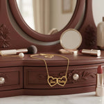 Two Hearts Necklace in gold with personalized engraving, symbolizing love and bond on a vanity.